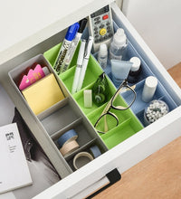 Clear plastic storage tray with dividers, used for organizing various small craft items.