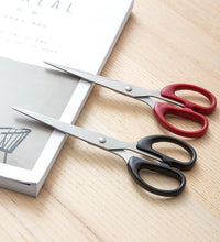 Top-down view of the scissors, emphasizing their stainless steel blades and plastic handle grip