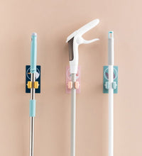 Self-adhesive mop and broom organizer for space-saving storage.